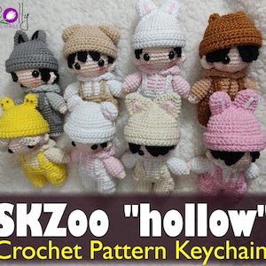 May include: A selection of handmade crochet keychains in a variety of colours, including grey, beige, white, brown, yellow, and pink. Each keychain depicts a small doll wearing a hat with animal ears. The text "SKZoo 'hollow' Crochet Pattern Keychain" is visible.