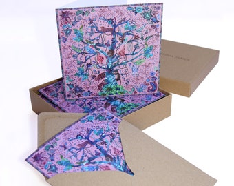May include: A set of greeting cards with a pink background and a colorful tree design. The cards are packaged in a brown box with a white envelope.