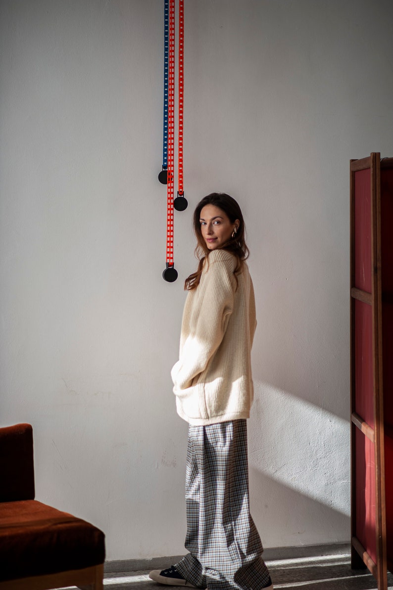 Relaxed silhouette winter sweater with a V-neckline, raglan sleeves, front pockets, and a button closure. Made of New Zealand Merino wool