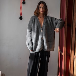 Oversized V-neck sweater with raglan sleeves and front pockets. Crafted from pure merino wool