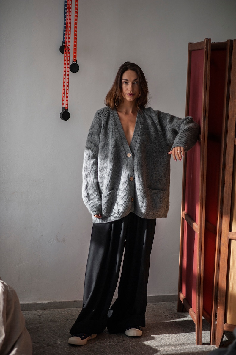 Oversized V-neck sweater with raglan sleeves and front pockets. Crafted from pure merino wool