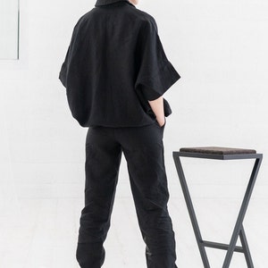 K&ouml;nnte beinhalten: Ein schwarzes Leinenhemd und eine Hose im Set mit lockerer Passform. Das Hemd hat einen Kragen und kurze &Auml;rmel. Die Hose hat einen Kordelzugbund und einen umgeschlagenen Saum.