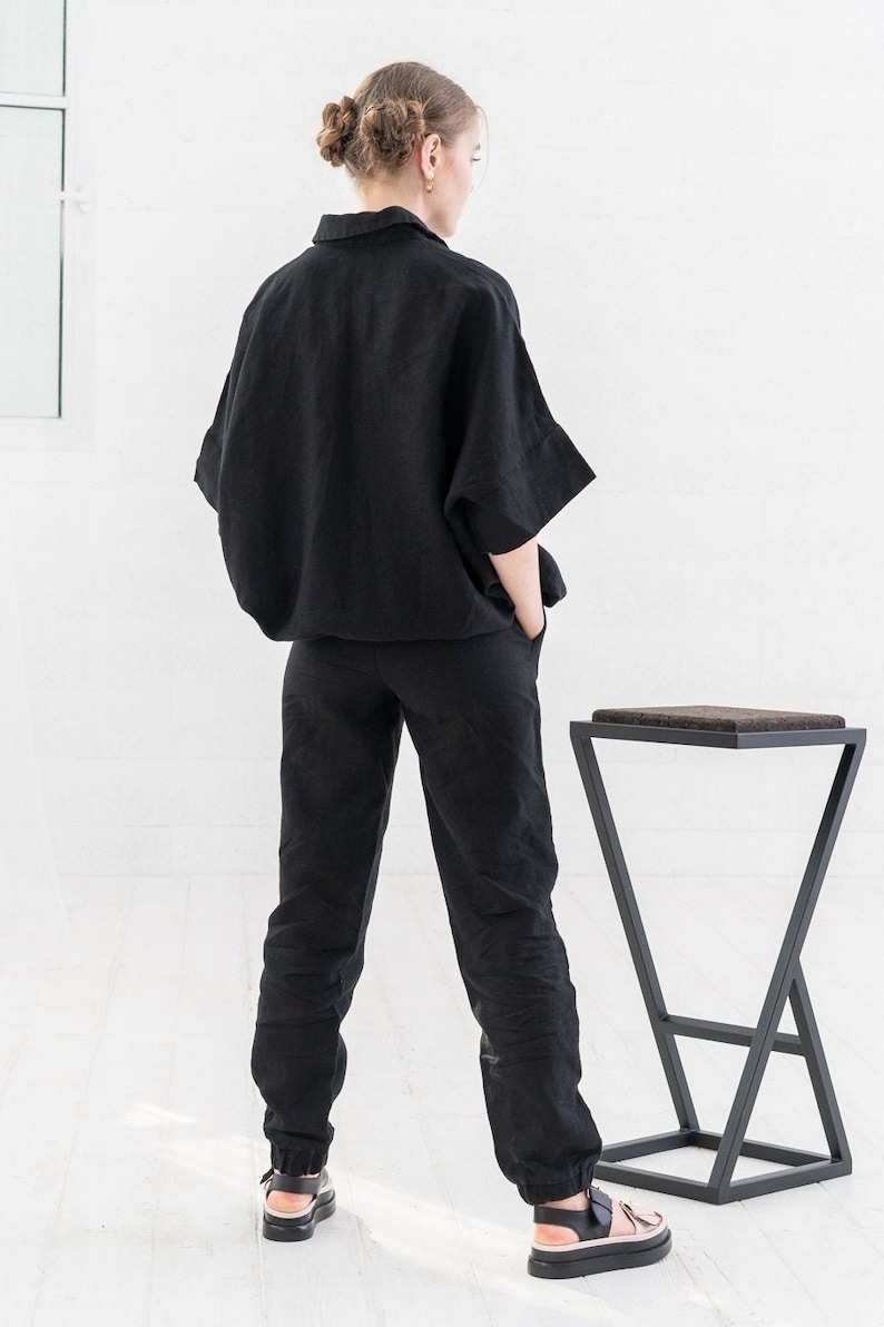 K&ouml;nnte beinhalten: Ein schwarzes Leinenhemd und eine Hose im Set mit lockerer Passform. Das Hemd hat einen Kragen und kurze &Auml;rmel. Die Hose hat einen Kordelzugbund und einen umgeschlagenen Saum.