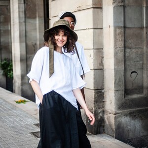 Minimalist linen outfit of a white T-shirt and black wide-leg trousers with pockets and an elastic waistband.