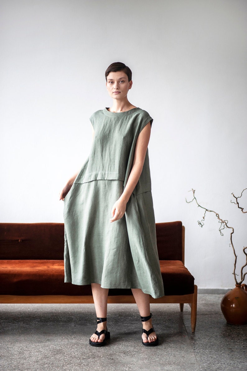 Voluminous linen dress with dropped shoulders, side pockets, and a crewneck. The dress features a folded detail in the waistline.