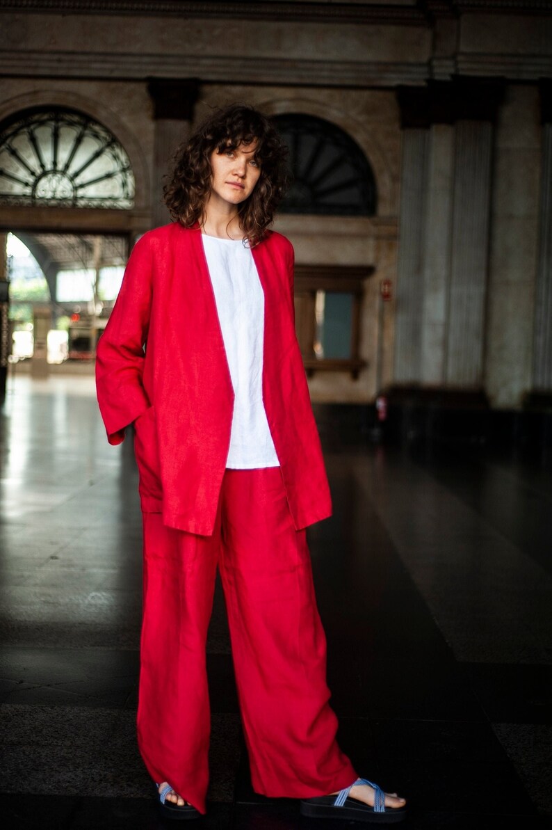 A woman in two-piece linen suit featuring wide-leg linen pants and a matching color wide sleeve linen blazer. Red color, relaxed silhouette.