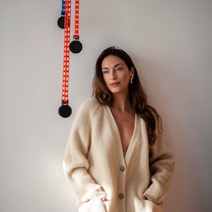 Oversized merino wool sweater with raglan sleeves, front pockets and coconut buttons