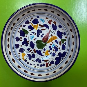 Pode incluir: Uma tigela de cer&acirc;mica branca com uma borda azul e um desenho floral azul, verde, amarelo e castanho com um p&aacute;ssaro. A tigela tem um fundo branco com uma borda azul e branca.