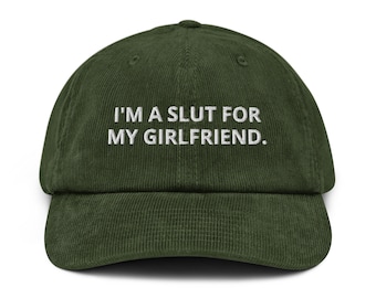 May include: A dark green corduroy baseball cap with a curved brim. The cap features white embroidered text that reads "I'M A SLUT FOR MY GIRLFRIEND."