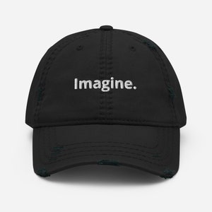 Op de afbeelding: Zwarte distressed baseball cap met het woord "Imagine" in het wit geborduurd. De cap heeft een gebogen klep en een versleten, vintage look, met distressed details rond de randen.