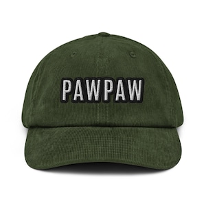 May include: A green corduroy baseball cap with the word "PAWPAW" embroidered in white block letters. The hat has a curved brim and a structured crown. The text is outlined in black.