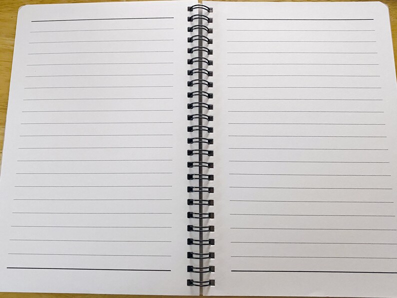 May include: A white spiral bound notebook with lined pages. The notebook is open to a blank page.