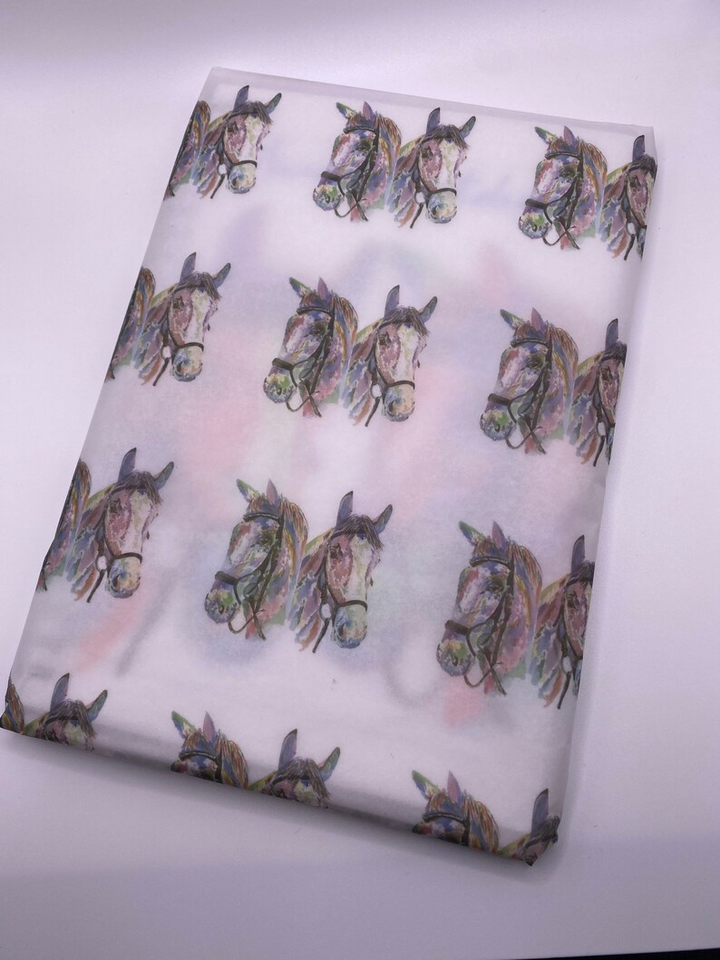 May include: White tissue paper with a repeating pattern of watercolour horse heads. The horses are brown and white with black bridles.