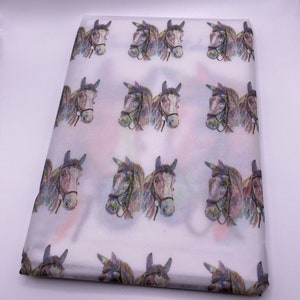 May include: White tissue paper with a repeating pattern of watercolour horse heads. The horses are brown and white with purple, blue, and green accents.