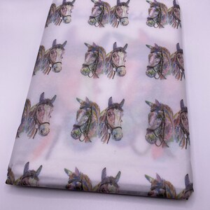 May include: White tissue paper with a repeating pattern of watercolour horse heads. The horses are brown with purple, blue, and green accents.