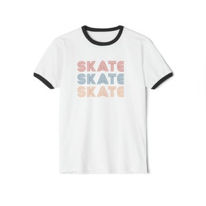Op de afbeelding: Wit T-shirt met een zwarte boord en een afbeelding van het woord "SKATE" dat drie keer wordt herhaald in verschillende kleuren.
