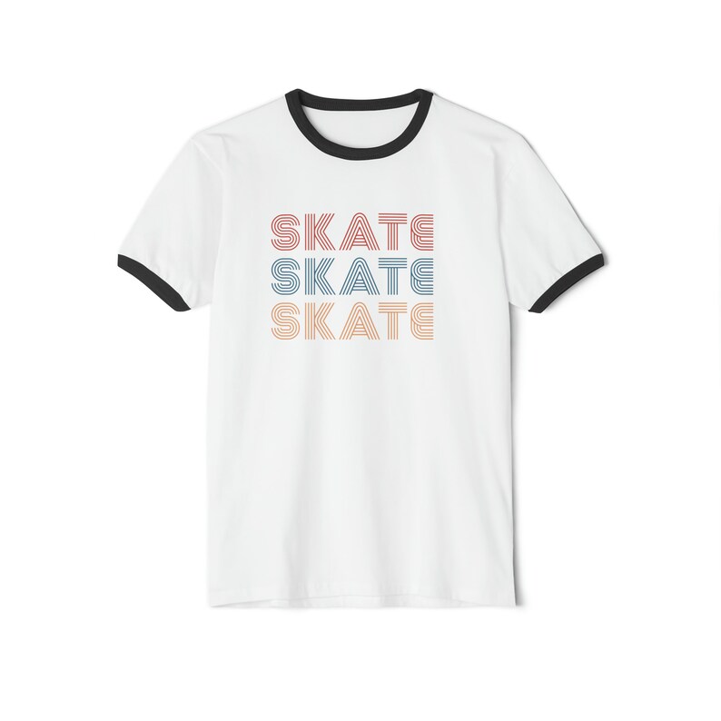 Op de afbeelding: Wit T-shirt met een zwarte boord en een afbeelding van het woord "SKATE" dat drie keer wordt herhaald in verschillende kleuren.