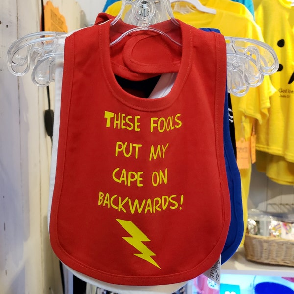 These fools put my cape on backwards, 100% cotton infant bib w/ Velcro closure. Baby humor | superhero | caped crusader | lightning bolt