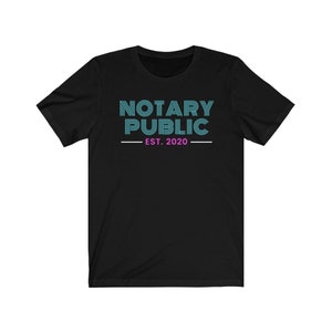 May include: Black t-shirt with the text "NOTARY PUBLIC" in teal blue with a pink "EST. 2020" underneath.