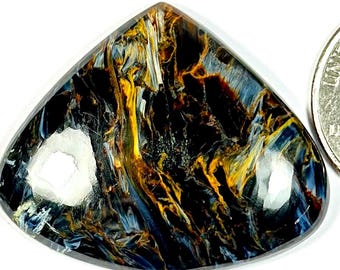 Peut inclure: Un cabochon de pierre de œil de tigre bleu, or et noir de forme triangulaire. La pierre précieuse est à peu près de la taille d'une pièce de 25 cents américaine.