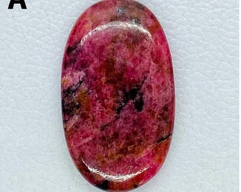 May include: A smooth, oval-shaped pink and brown gemstone with a polished finish.