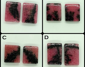 Pode incluir: Quatro pares de cabochões retangulares de rodonita rotulados A, B, C e D. Cada pedra polida apresenta uma cor de base rosa vibrante com inclusões dendríticas pretas distintas e irregulares espalhadas pela superfície em padrões únicos.