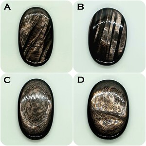Puede incluir: Cuatro cabujones ovalados de obsidiana negra con patrones de brillo plateado metálico. Cada piedra muestra una textura reflectante única, que va desde rayas diagonales hasta diseños circulares concéntricos de veta de madera sobre una superficie pulida.
