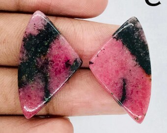 May include: Two pink and black triangle-shaped cabochon gemstones. The stones have a marbled pattern of pink and black.