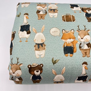May include: A light blue fabric with a repeating pattern of various animals wearing clothes and hats. The animals include a deer, a fox, a rabbit, a goose, and a bear. The fabric has a subtle texture and a light green background.