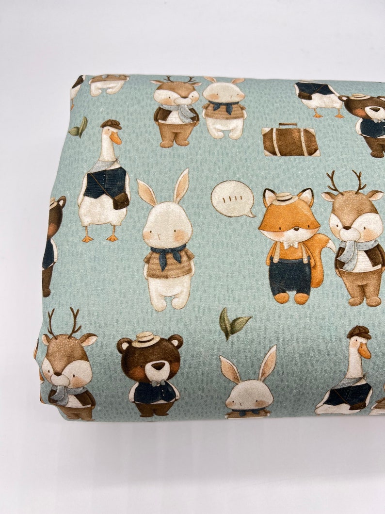 May include: A light blue fabric with a repeating pattern of various animals wearing clothes and hats. The animals include a deer, a fox, a rabbit, a goose, and a bear. The fabric has a subtle texture and a light green background.