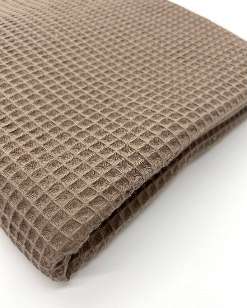 May include: A brown waffle weave fabric folded in half. The fabric has a textured surface and a soft, plush feel.