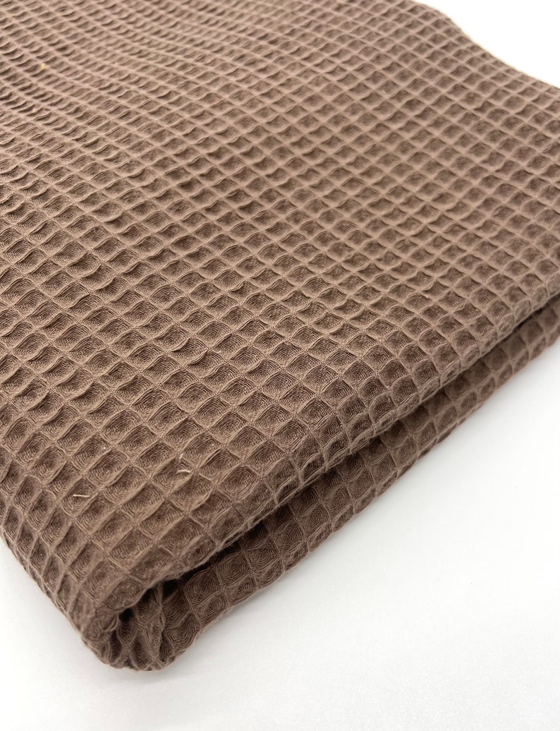 May include: A brown waffle weave fabric folded in half. The fabric has a textured, waffle-like pattern.