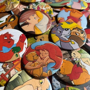 Puede incluir: Una colección de botones redondos y coloridos con varios personajes de dibujos animados. Los botones muestran personajes como Ariel, Winnie the Pooh y otros. Los botones son de varios colores y diseños.