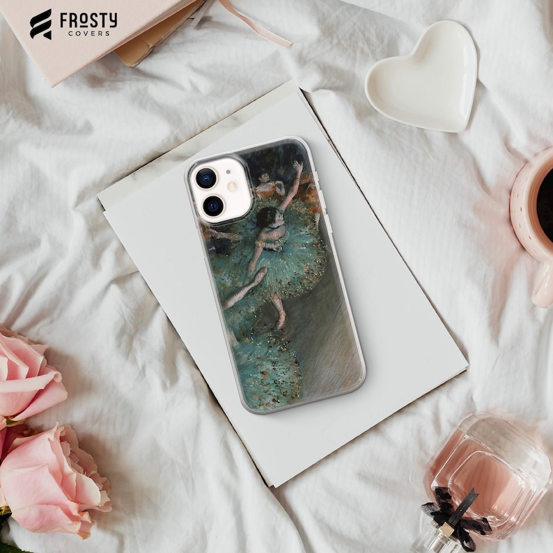 Pode incluir: Capa de telefone transparente com uma pintura de Degas de uma bailarina em um tutu verde. A capa tem uma borda transparente e est&aacute; colocada em uma superf&iacute;cie branca. A marca "Frosty Covers" &eacute; vis&iacute;vel em uma caixa no fundo.