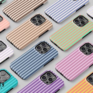 Puede incluir: Una colección de fundas para smartphone con varios patrones de rayas verticales en colores que incluyen melocotón, beige, verde, azul, morado, amarillo y rosa. Cada funda tiene un recorte negro para la cámara y el logo de Frosty Covers es visible.