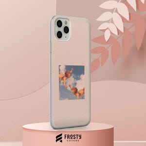 May include: A clear, glittery phone case featuring a square graphic of two cherubs floating among blue clouds. The case has a cutout for a triple-lens camera system on the back. The design is centered on the back of the phone case, showcasing a classic art-inspired print against a shimmering, translucent material.