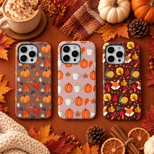 Op de afbeelding: Drie smartphonehoesjes met herfstpatronen. Het linkerhoesje heeft pompoenen, eikels en bladeren op een bruine achtergrond. Het middelste hoesje toont pompoenen en mokken op een lichtroze achtergrond. Het rechterhoesje toont vossen, slakken en bladeren op een donkerbruine achtergrond.
