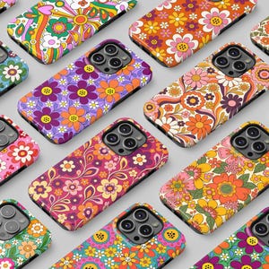 May include: A collection of smartphone cases arranged in a grid, each featuring a distinct, colorful floral pattern with various combinations of orange, pink, yellow, purple, green, and blue hues, all displaying a triple-lens camera cutout.
