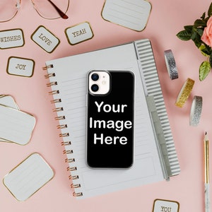 Może przedstawiać: Czarne etui na iPhone'a z białym obramowaniem i obiektywem aparatu. Na etui widnieje napis "Your Image Here". Etui leży na r&oacute;żowym tle obok notesu, oł&oacute;wk&oacute;w i ozdobnej taśmy washi.