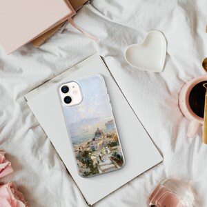 May include: A clear phone case with a painting of a cityscape on a white background. The painting features a white building with a dome and a blue sky.