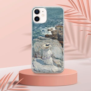 May include: A white iPhone case with a painting of a person in a white dress and a straw hat sitting on a rocky shore by the ocean. The painting is in a painterly style with blue, green, and white colors.