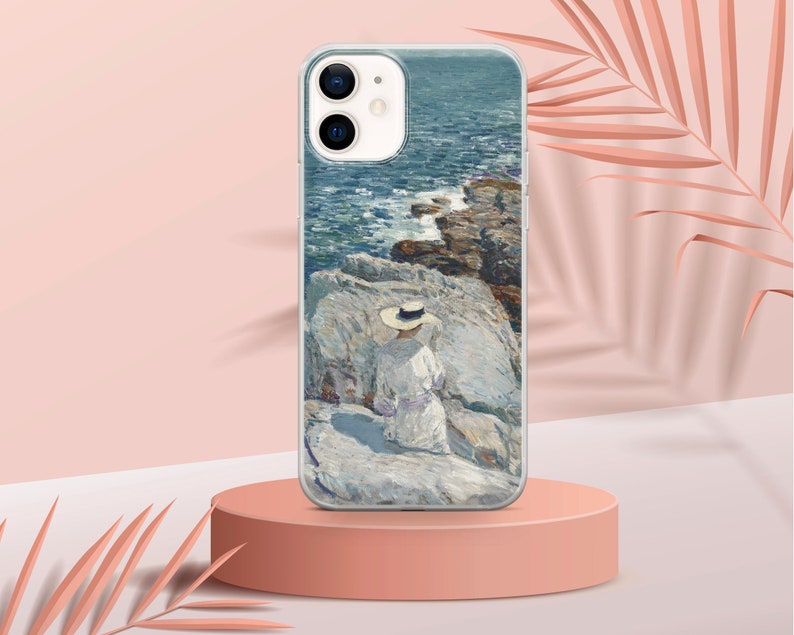 May include: A white iPhone case with a painting of a person in a white dress and a straw hat sitting on a rocky shore by the ocean. The painting is in a painterly style with blue, green, and white colors.