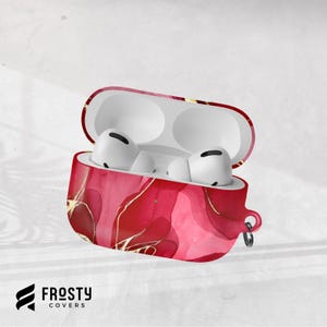 Könnte beinhalten: Rote und goldfarbene AirPod Pro-Hülle mit weißen AirPods im Inneren. Die Hülle hat ein lebendiges, abstraktes Design mit glänzendem Finish. Die Hülle ist geöffnet und zeigt die weißen Ohrhörer. Der Markenname "Frosty Covers" steht unten.