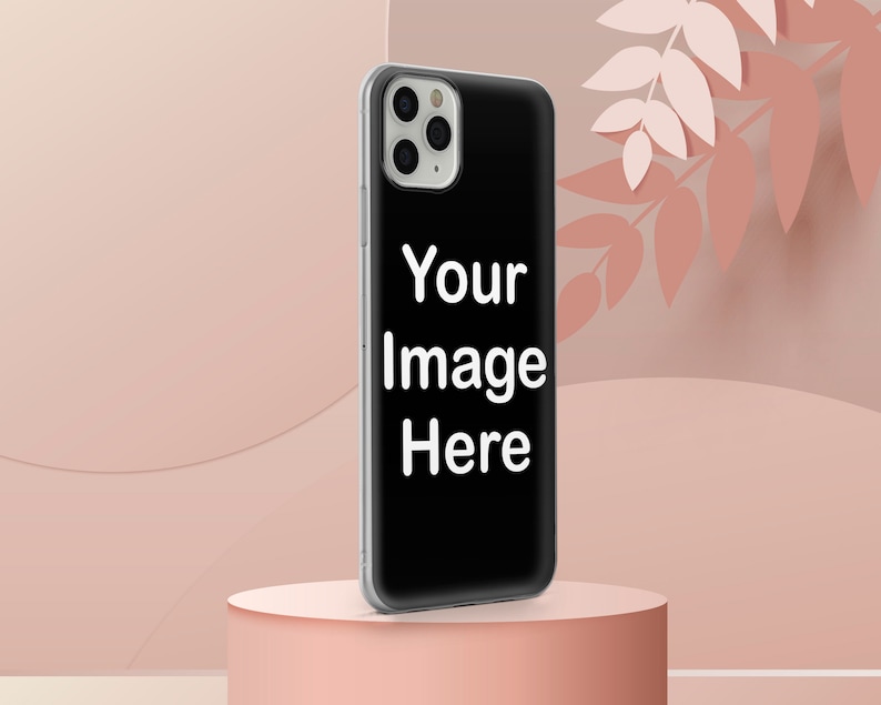 Może przedstawiać: Czarne etui na telefon z białą ramką i wycięciem na obiektyw aparatu. Na etui widnieje napis "Your Image Here". Etui na telefon leży na r&oacute;żowym cokole.