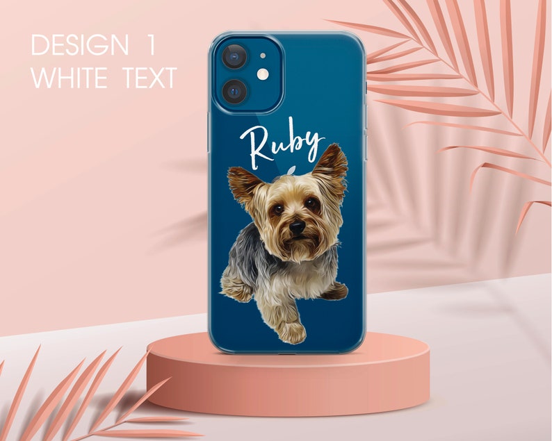 Pu&ograve; includere: Una custodia per telefono blu con un ritratto di cane Yorkshire Terrier e il nome "Ruby" in scrittura bianca. La custodia ha il testo "DESIGN 1 WHITE TEXT" in alto a sinistra. Il cane ha peli marroni e neri.