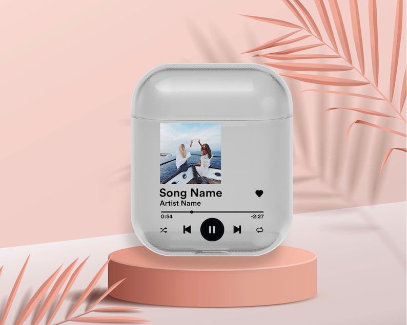 May include: A clear phone case with a photo of two people on a boat. The case has a music player design with the text "Song Name" and "Artist Name". The music player has a play button, a pause button, and a skip button.
