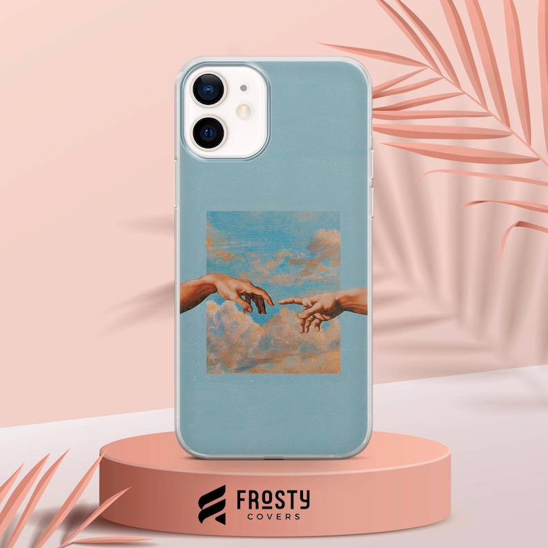 May include: A light blue smartphone case featuring a rectangular print of two hands reaching toward each other against a backdrop of clouds. The case has a clear border and a cutout for a dual-lens camera system on the upper left corner.