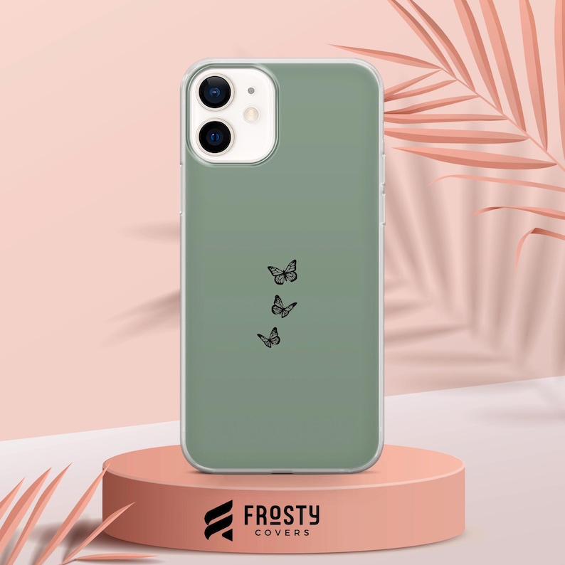 K&ouml;nnte beinhalten: Eine gr&uuml;ne Handyh&uuml;lle mit einem Design aus vier schwarzen Schmetterlingen. Die H&uuml;lle ist f&uuml;r ein iPhone konzipiert und hat ein klares Kameraobjektiv.