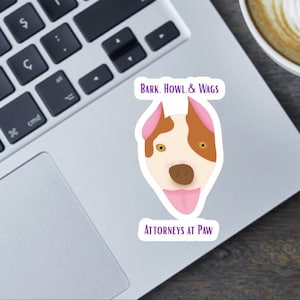 May include: A sticker with a cartoon dog face. The dog has brown and white fur, pink ears, and a pink tongue. The sticker has the text "BARK. HOWL. & WAGS" and "ATTORNEYS AT PAW" in purple.