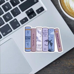 May include: A sticker of a stack of five books with dragon-themed titles. The books are purple, blue, and pink with white text. The titles are "Dragon Born Legend", "The Last Wyrm", "Fire Wings", "Dragon Kin", and "Draconomicon".